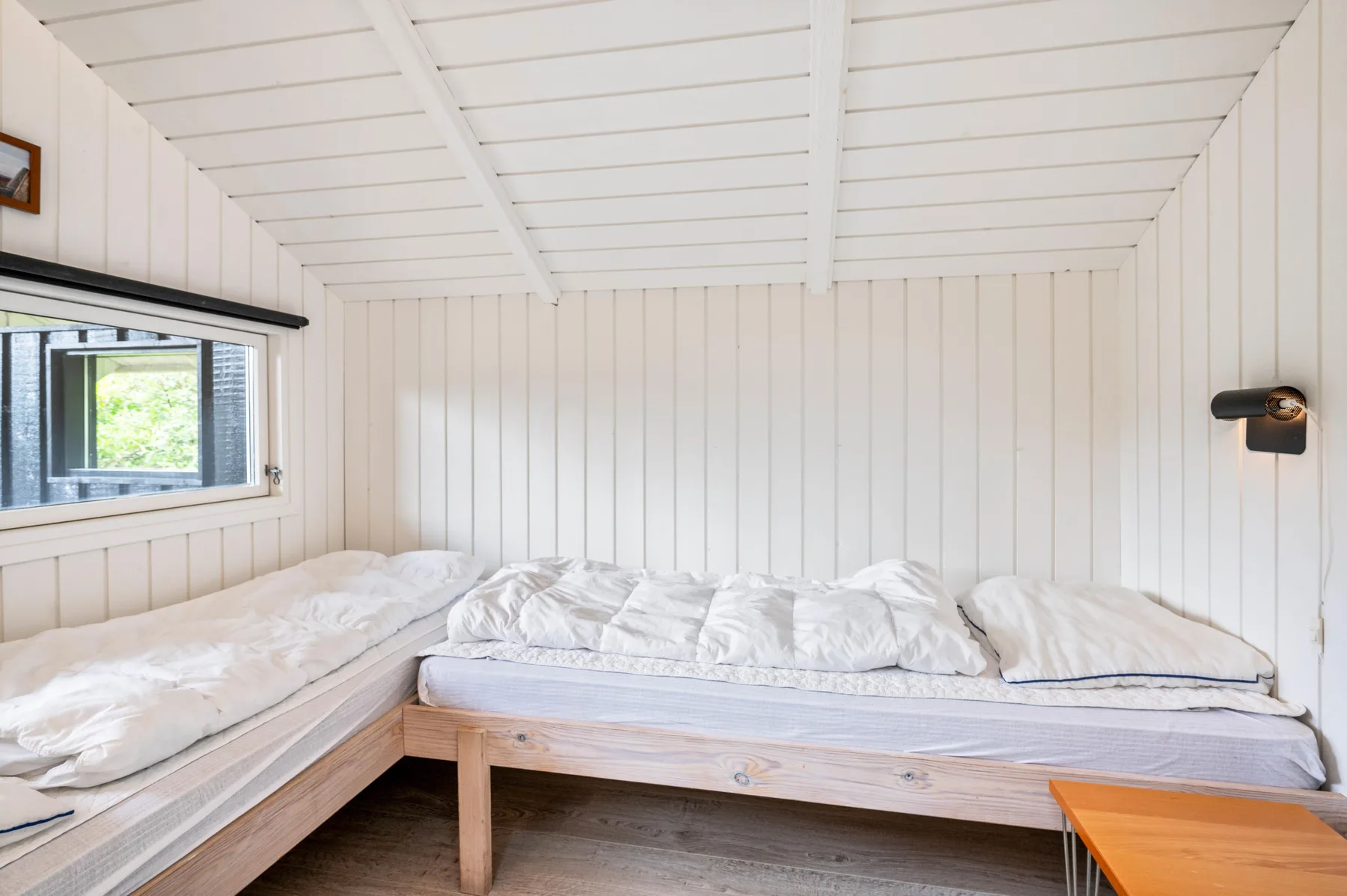 A bright bedroom with a bed beneath a white paneled ceiling.