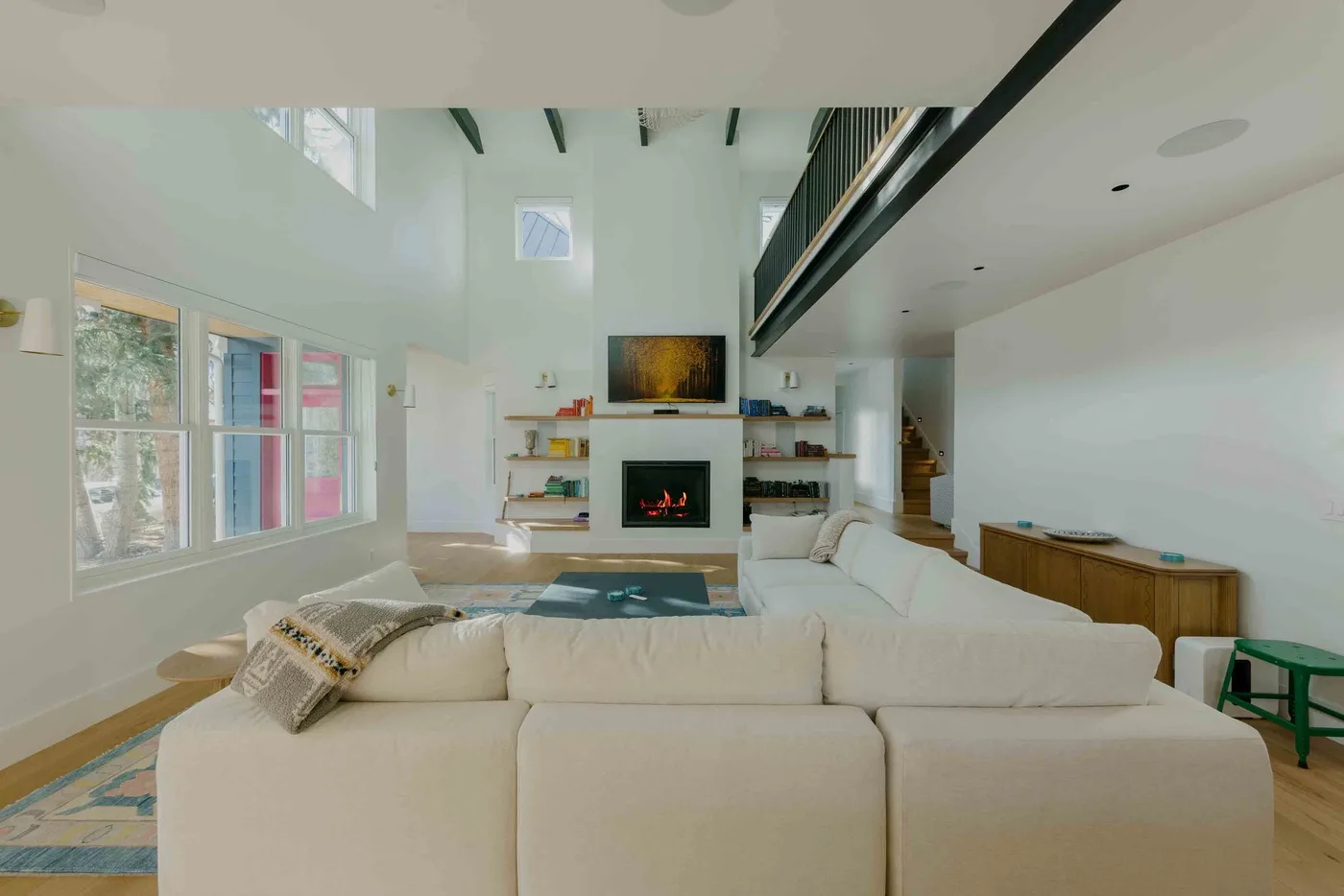 Una sala luminosa con asientos blancos, grandes ventanas y una chimenea.