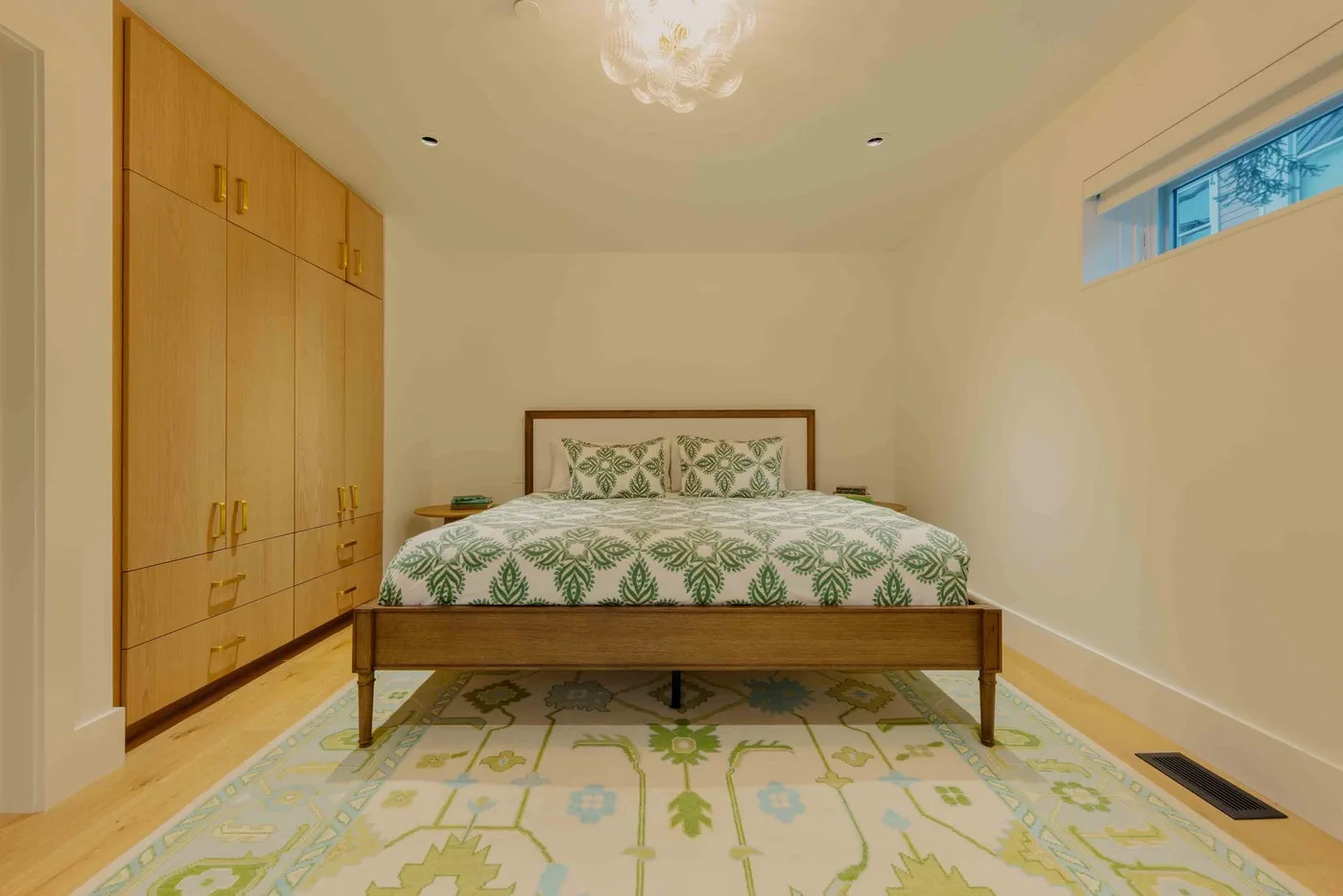 Un dormitorio con una cama vestida con ropa de cama estampada en verde y una alfombra grande.