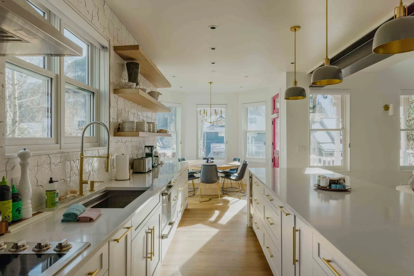 Una cocina luminosa con una isla larga y un comedor junto a las ventanas.