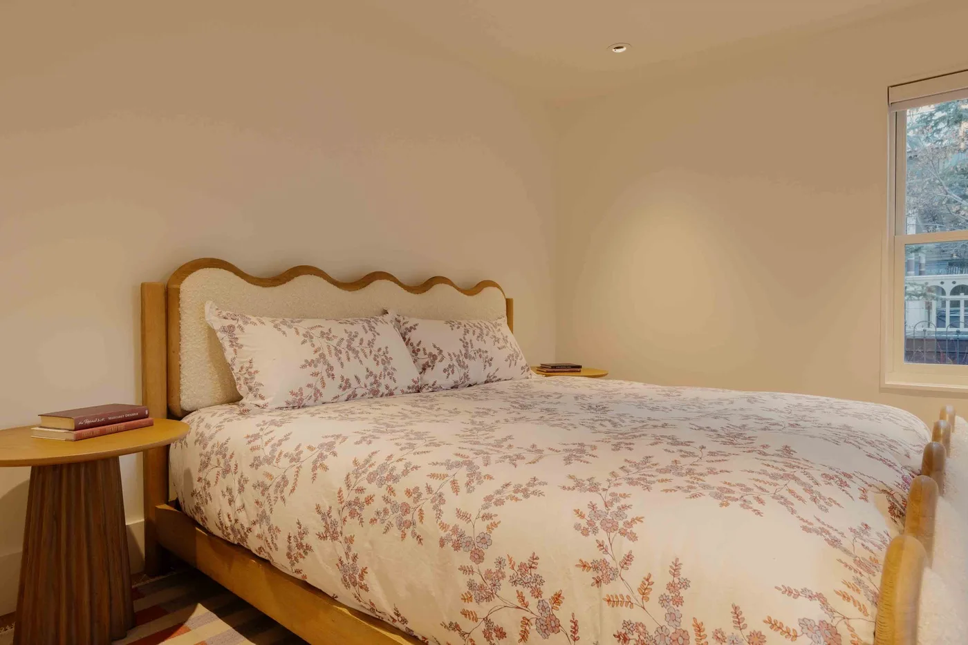 Un dormitorio con una cama de estampado floral junto a una ventana.