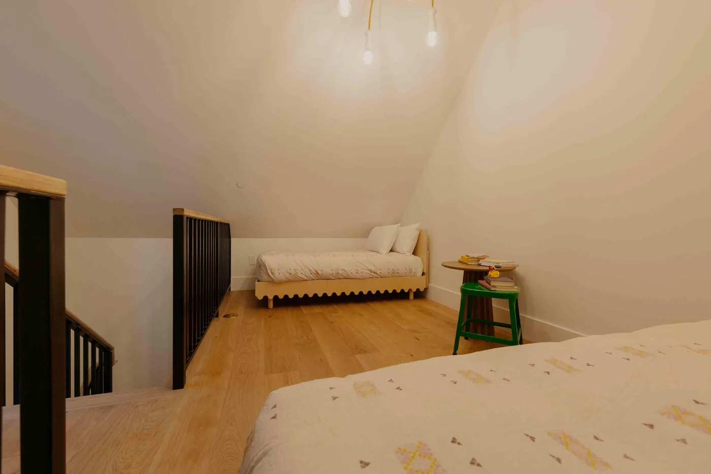 Un dormitorio con dos camas y una mesita junto a la cama del fondo.