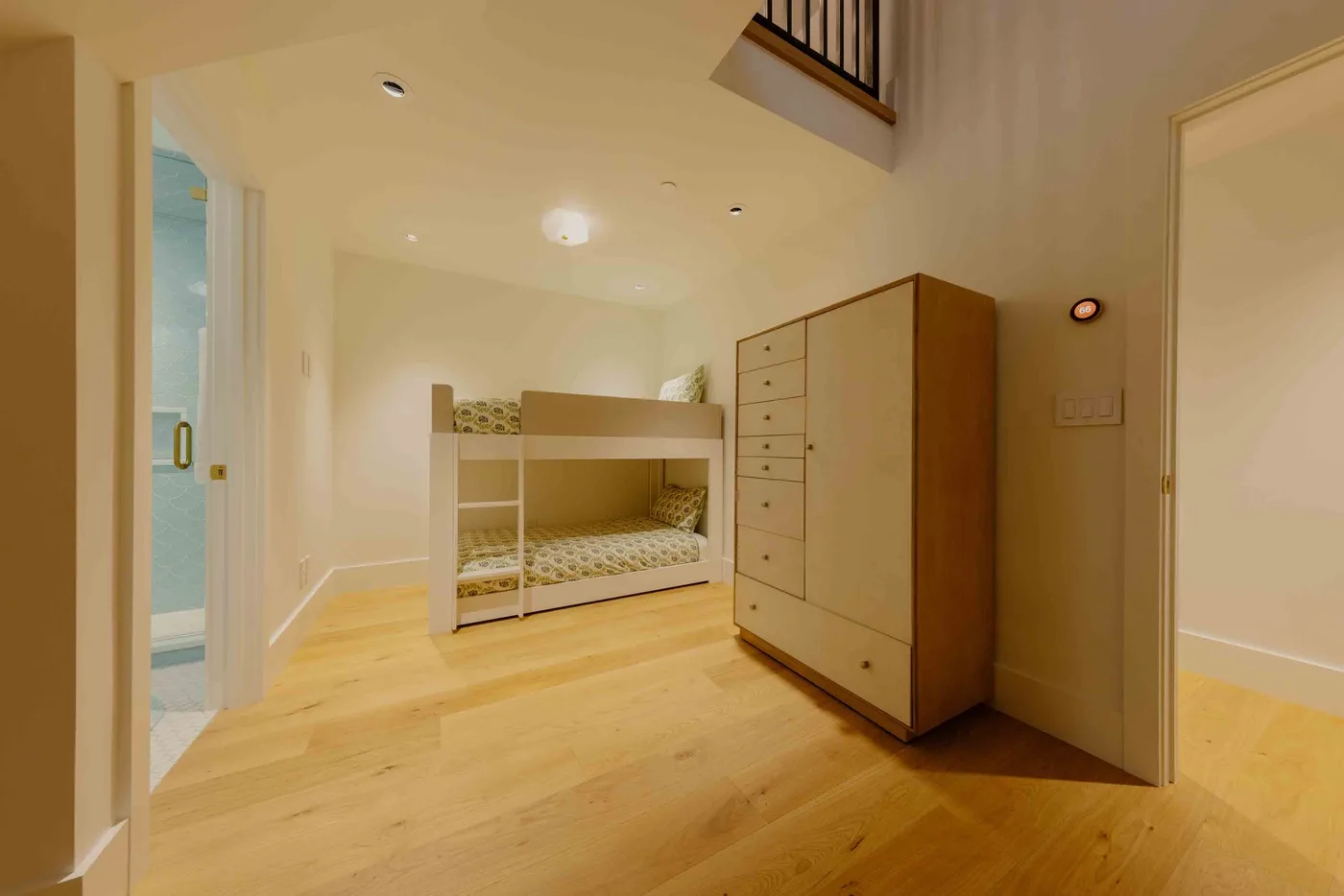 Un dormitorio luminoso con una litera de madera y una cómoda alta.