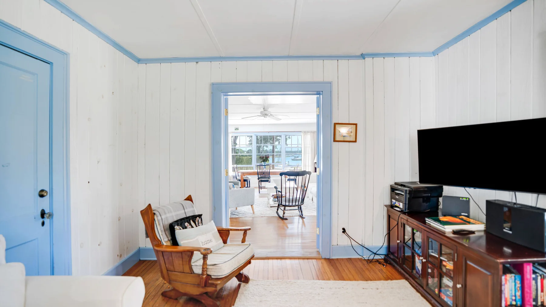 A bright living room with wooden seating and a television beside the doorway.