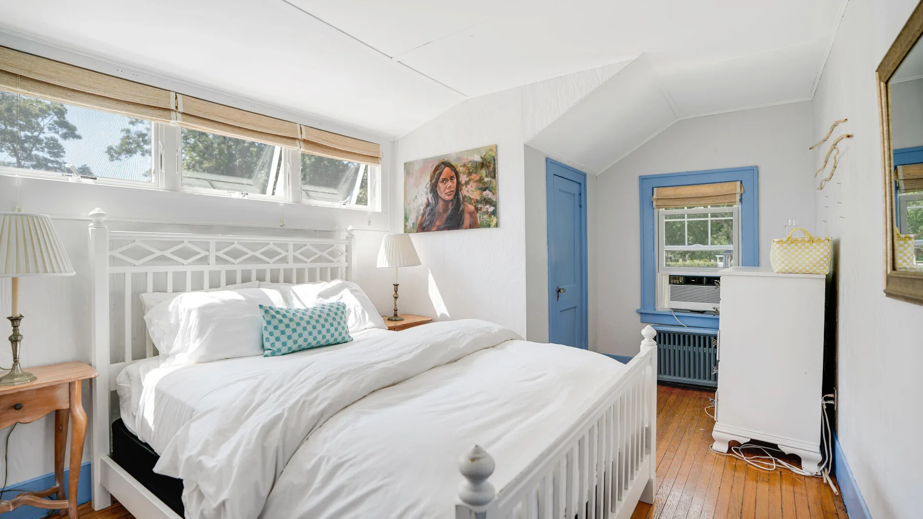 A bright bedroom with a white bed and blue trim around the doorway and window.