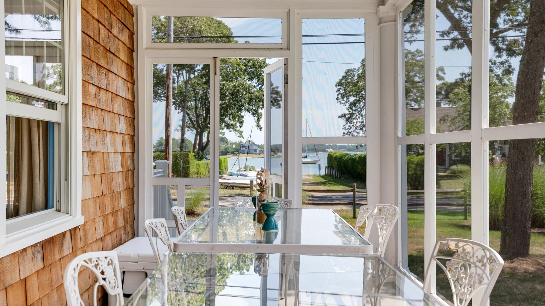 A bright sunroom with a glass dining table and large windows.
