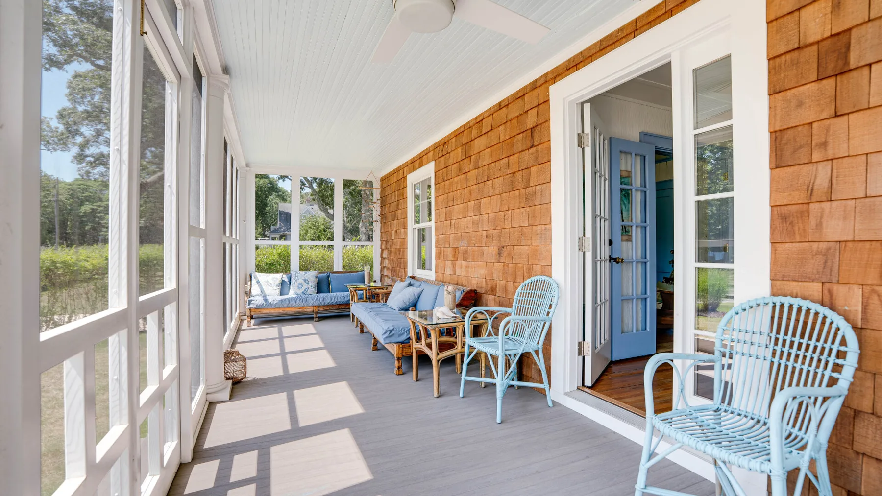 A bright sunroom with blue seating and large windows overlooking greenery.