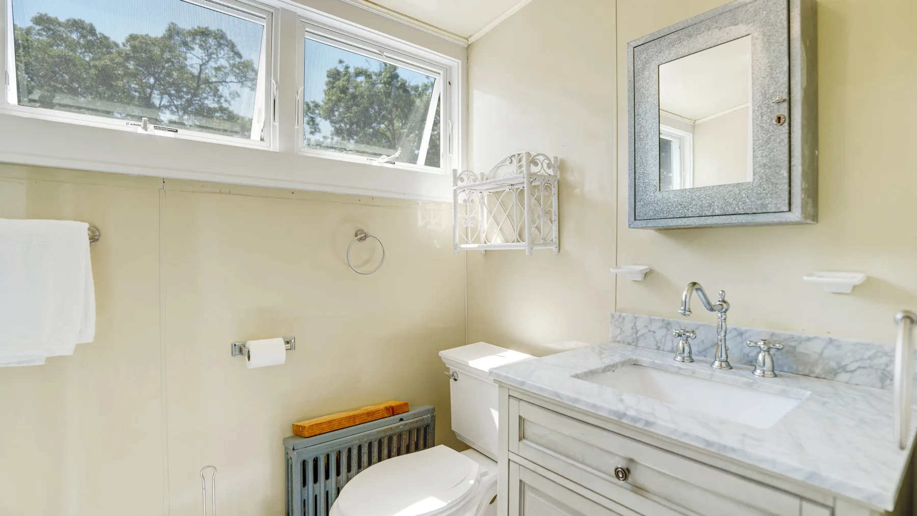 A bright bathroom with a bathtub, toilet, and sink beneath high windows.