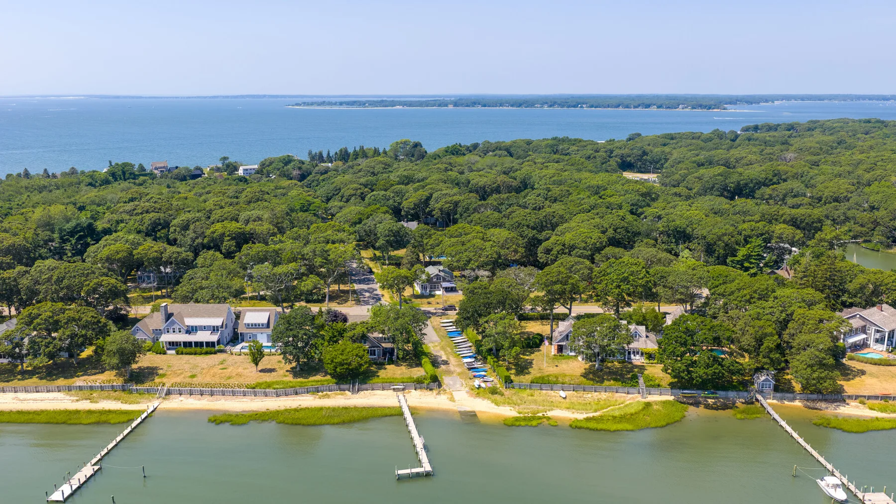 Aerial view of a wooded waterfront with homes, docks, and open water.