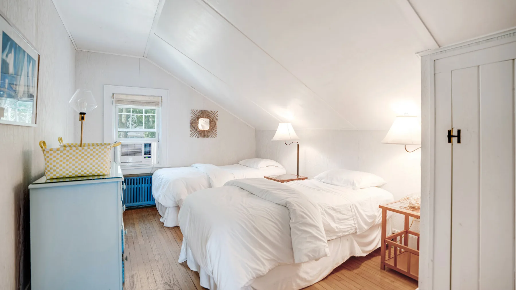 A bright bedroom with two beds and a window.