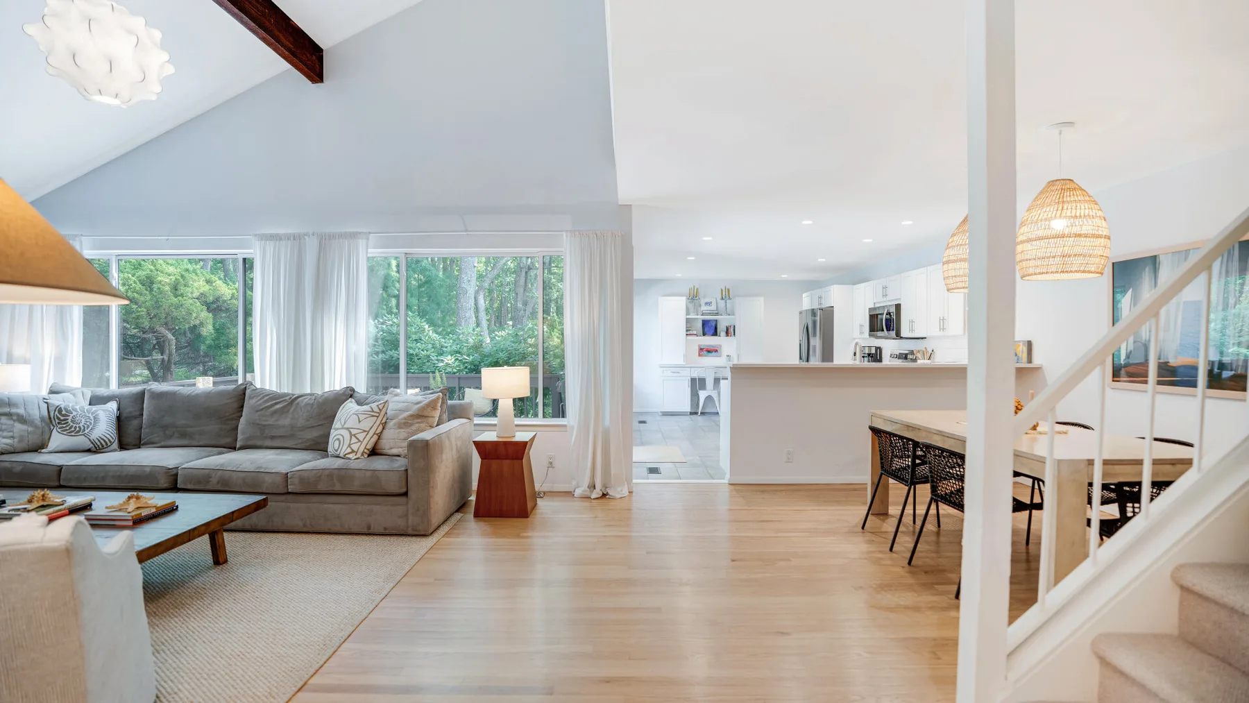 Una sala de estar y cocina de planta abierta, con una zona de asientos junto a grandes ventanas.
