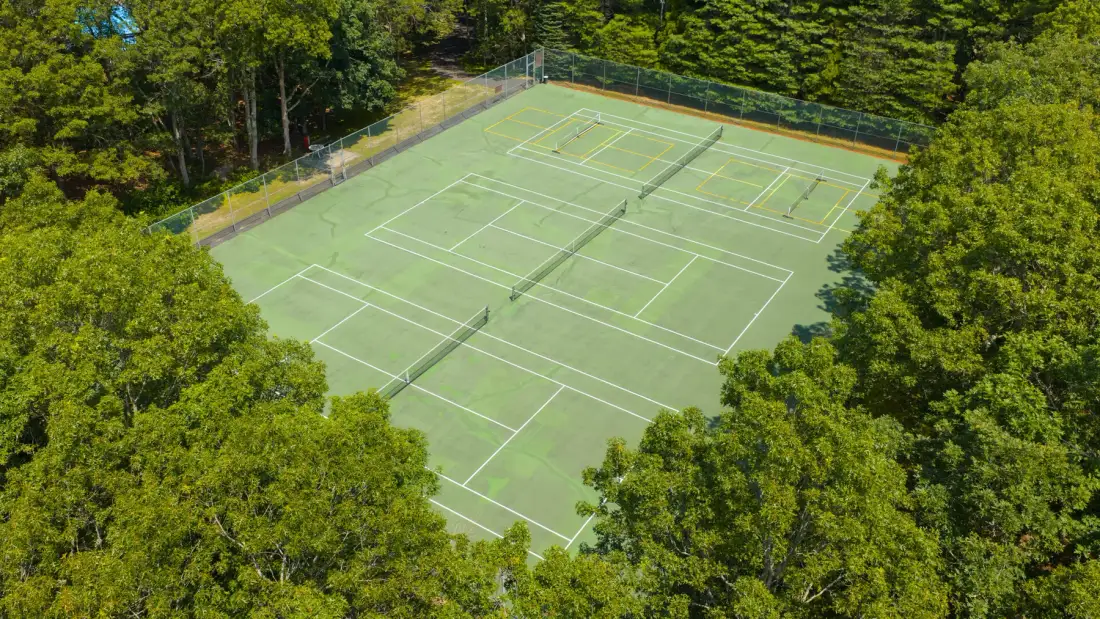 Aerial view of outdoor tennis courts surrounded by trees.