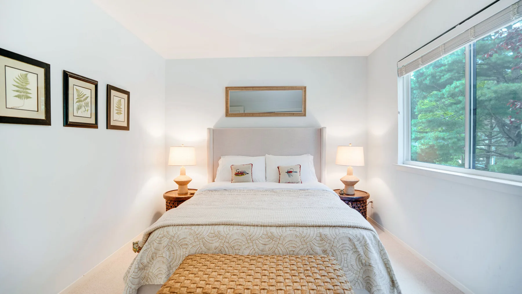 Un dormitorio luminoso con una cama bien tendida y una ventana grande.