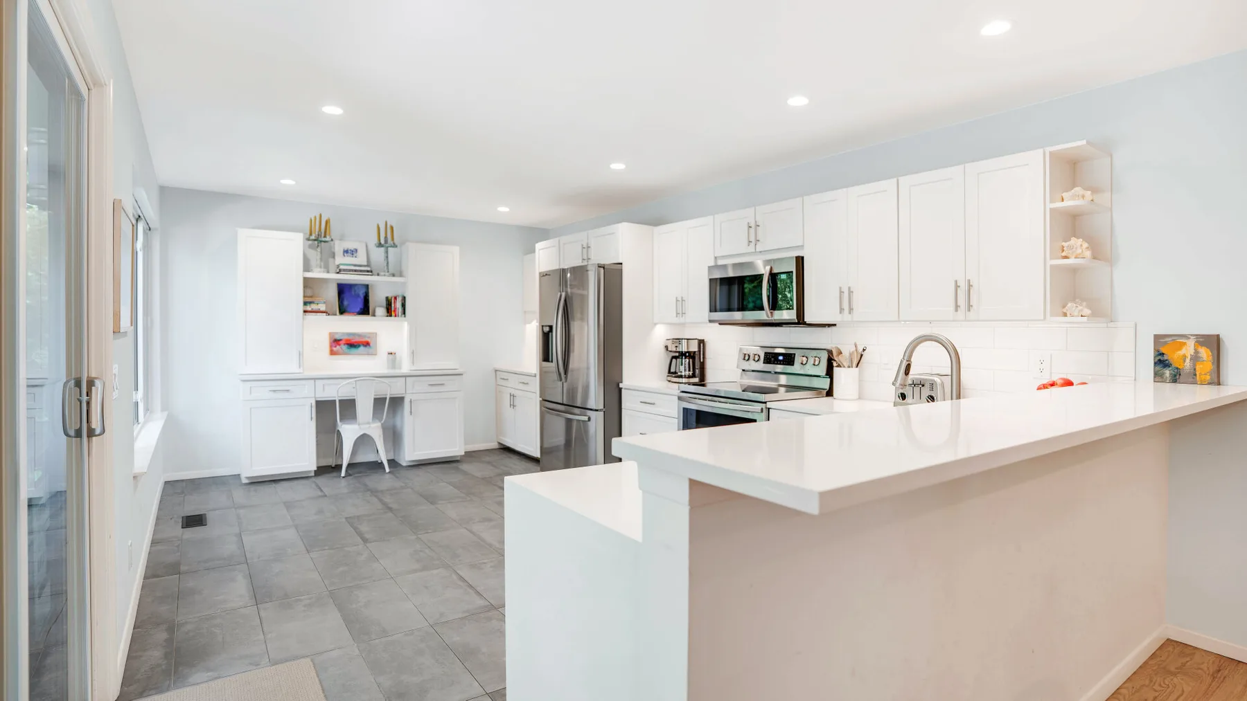 Una cocina luminosa con gabinetes blancos, electrodomésticos de acero inoxidable y una isla grande.