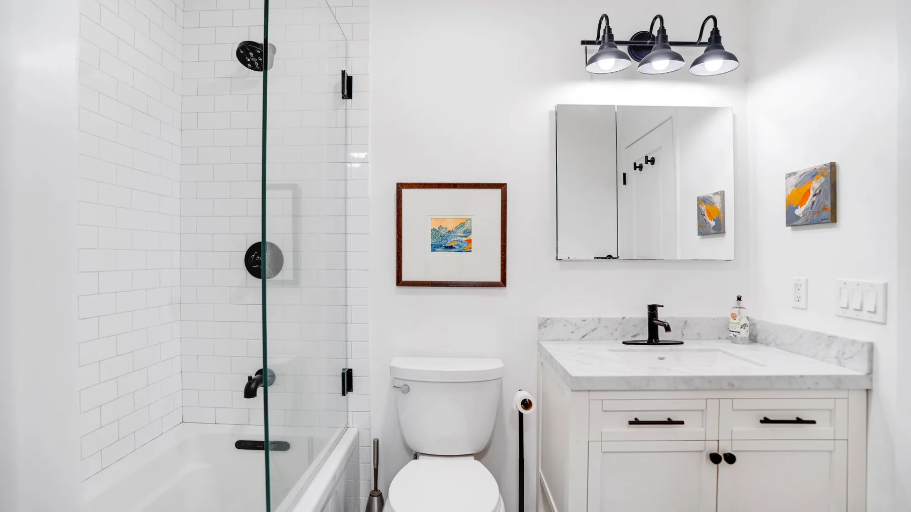 Un baño luminoso con ducha de vidrio, inodoro y tocador.