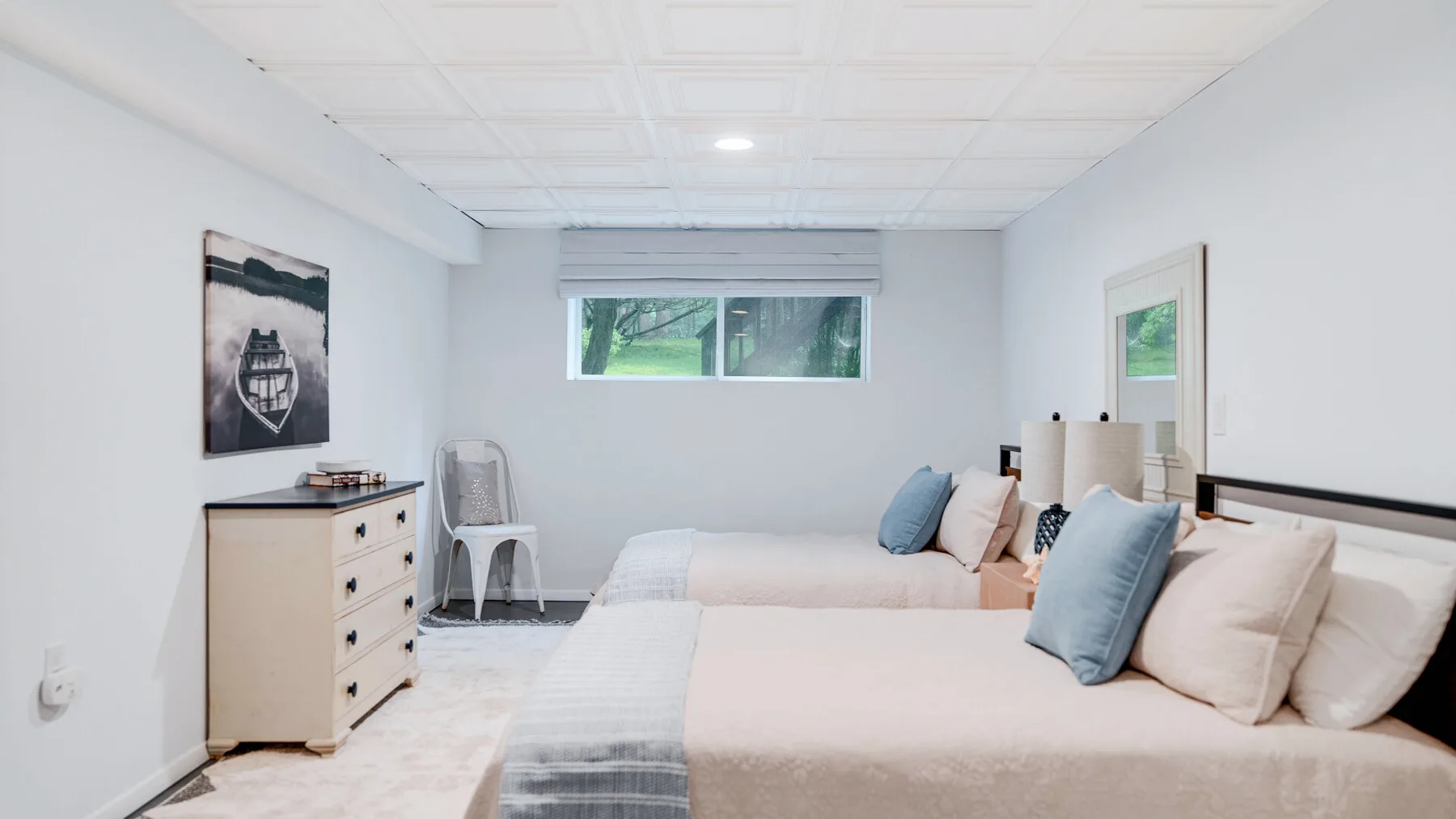 Un dormitorio luminoso con dos camas y una ventana pequeña.