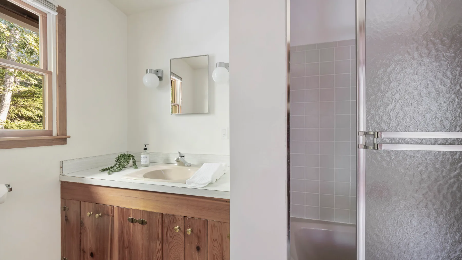 A bathroom vanity with a sink sits beside a tiled shower.