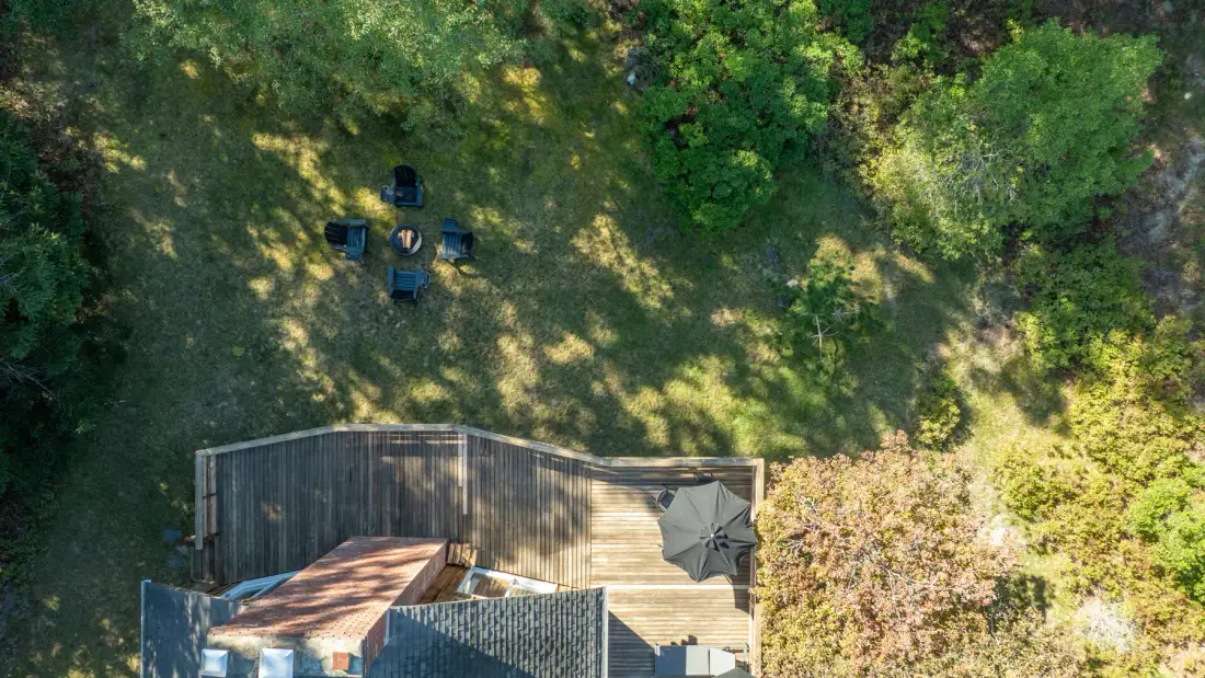 An aerial view of a wooden deck beside a grassy clearing and surrounding trees.