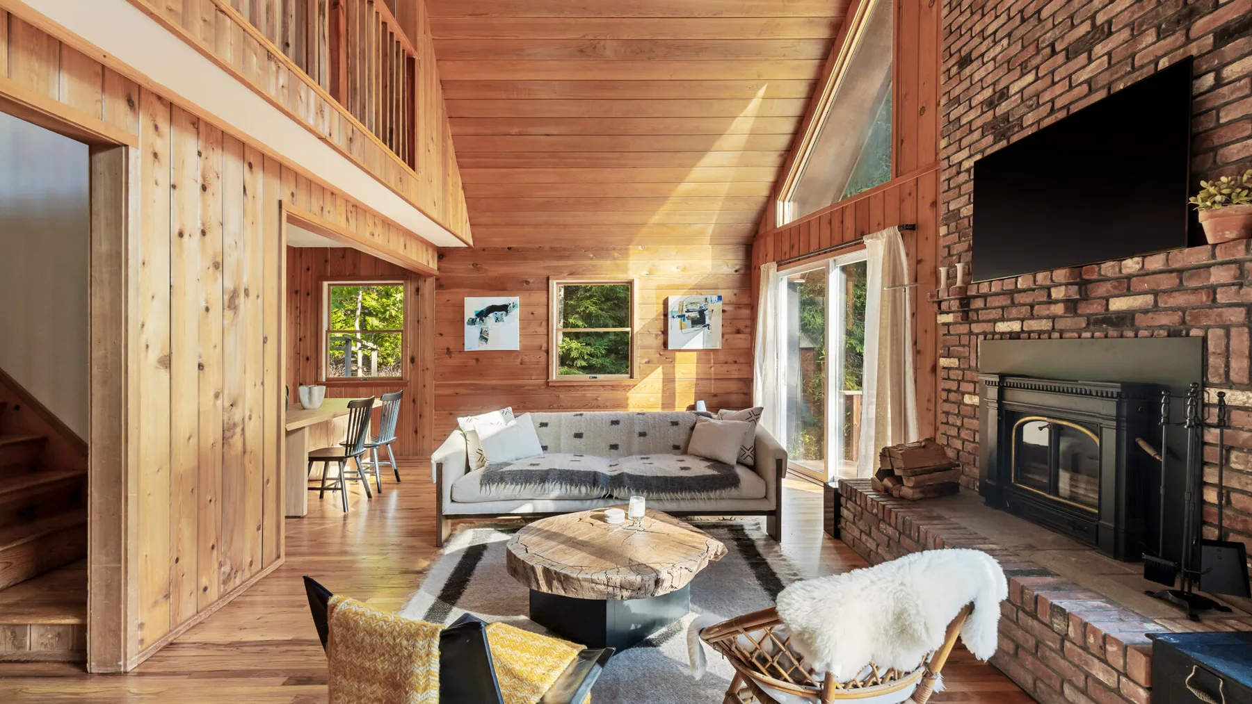 A wood-paneled living room with seating, a fireplace, and large windows.