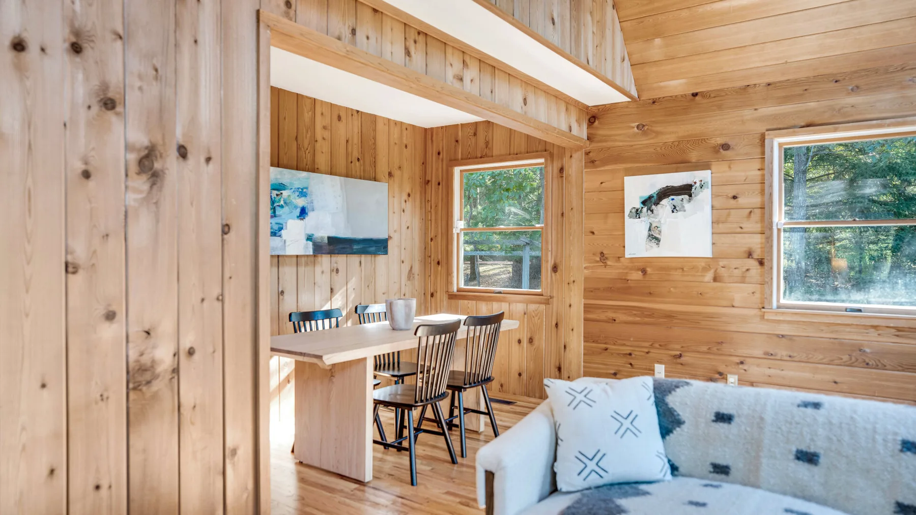 A wood-paneled living area with a sofa beside a dining table.