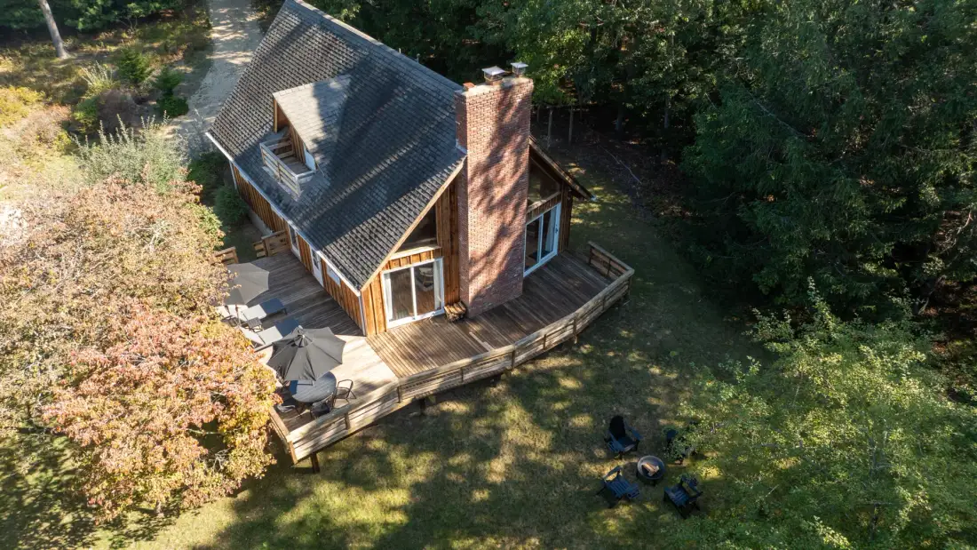 A wooded house with a raised deck and a grassy yard.