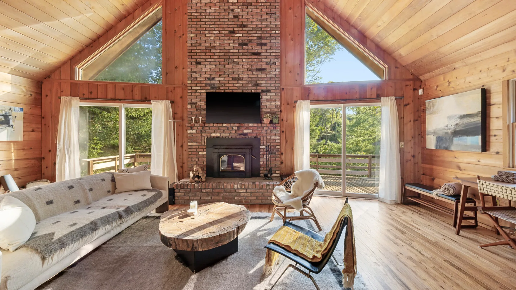 A wood-paneled living room with a stone fireplace and seating.