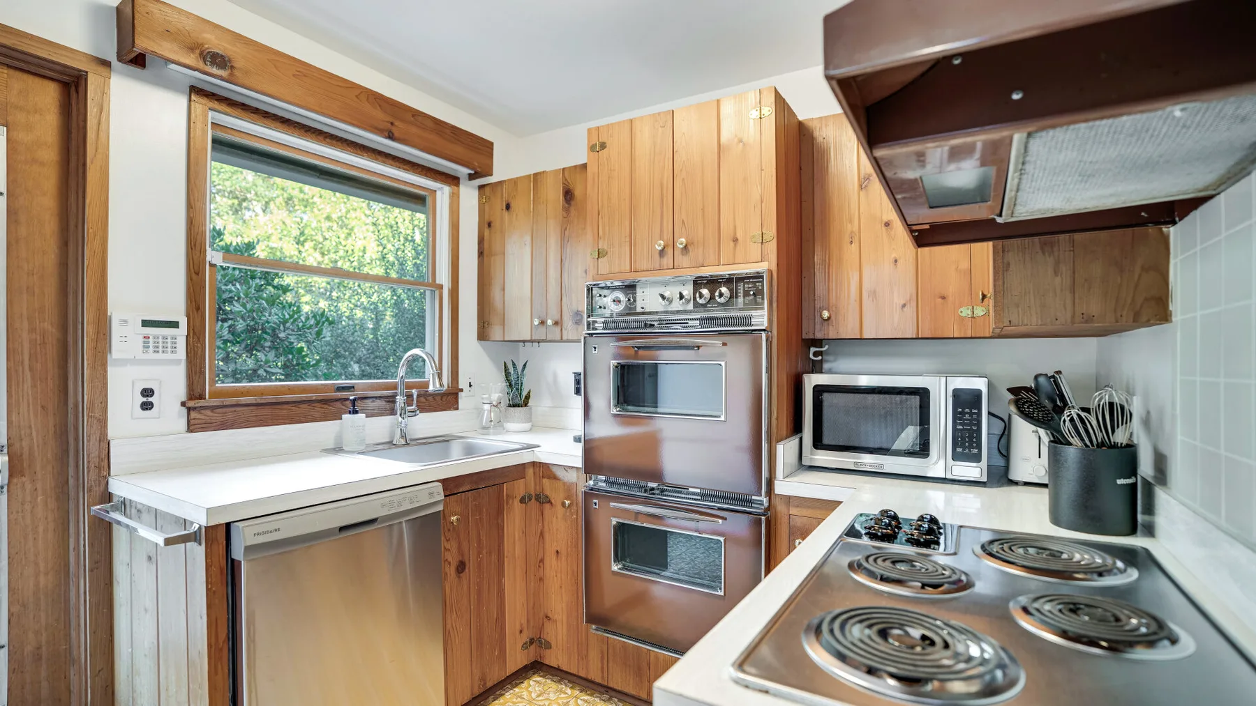 A wood-cabinet kitchen with an oven, microwave, and electric stovetop.