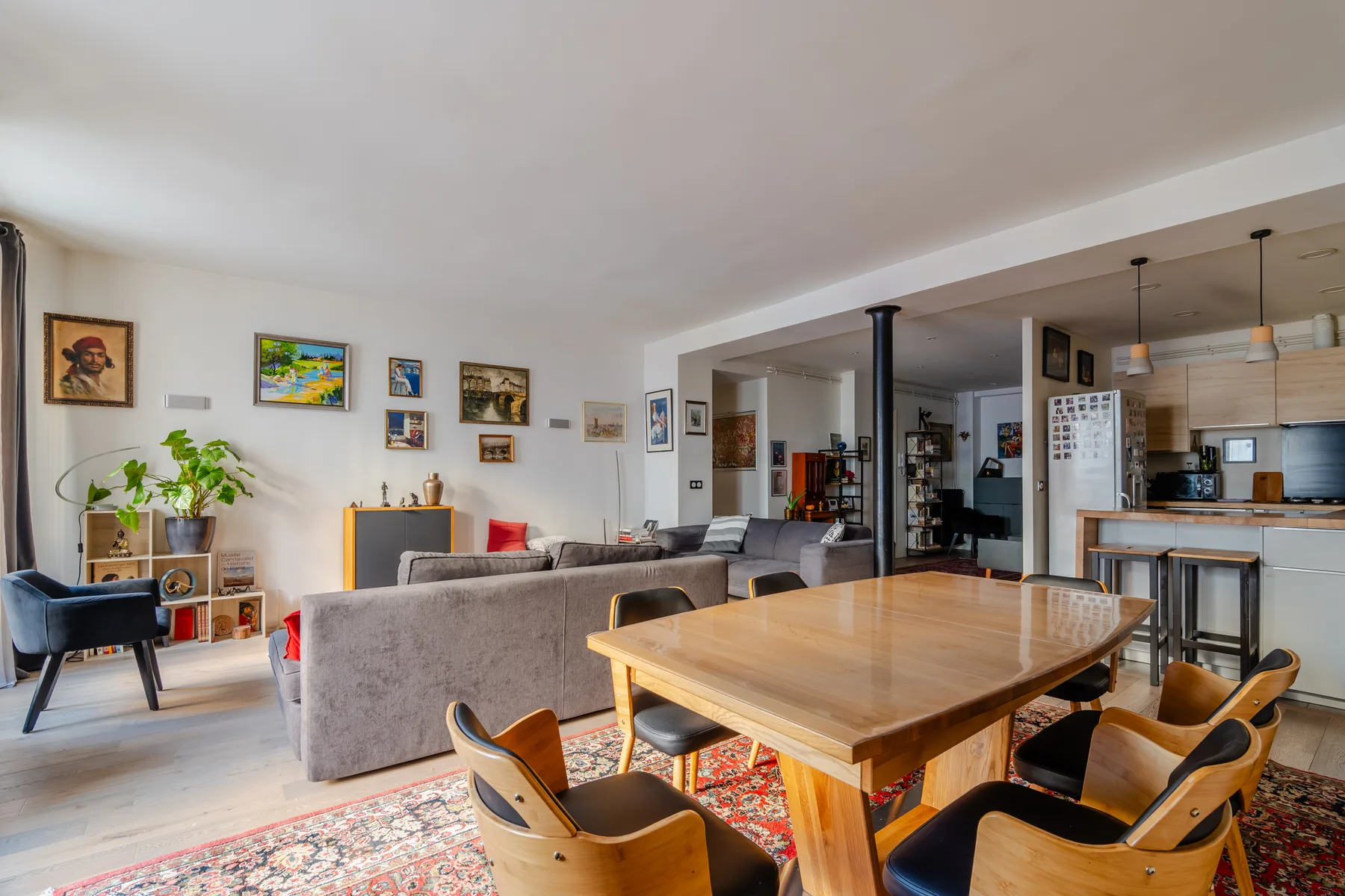 An open-plan living and dining area with seating, a wooden table, and a kitchen.