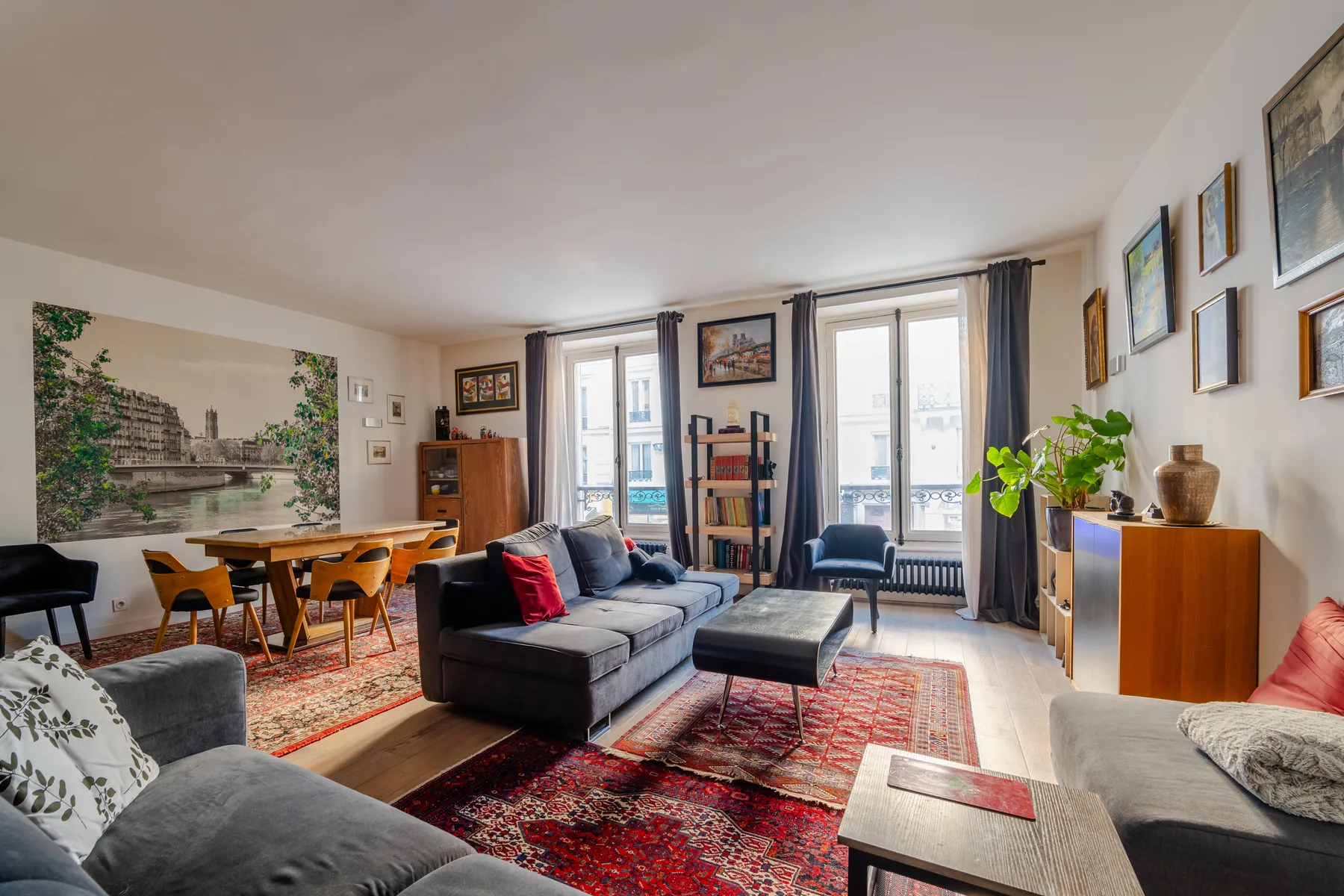A bright living room with seating arranged around a coffee table and red rugs.