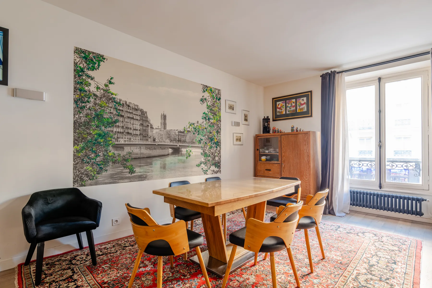A dining area with a wooden table and chairs on a patterned rug.