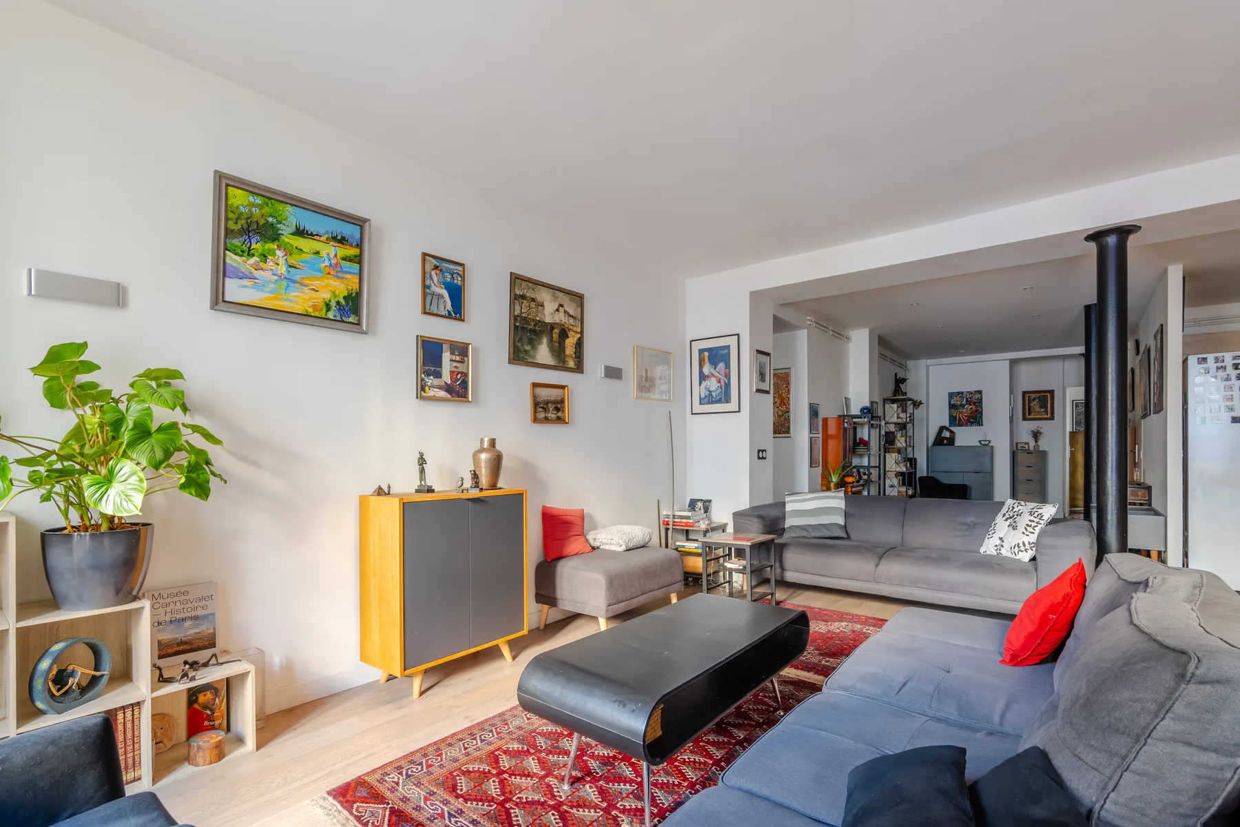 A bright living room with seating, a low coffee table, and framed artwork.
