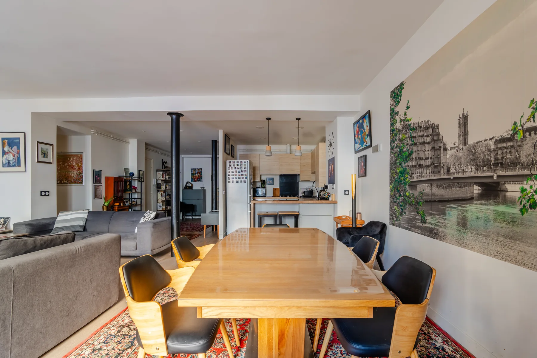 An open-plan dining and living area with a long wooden table and surrounding seating.