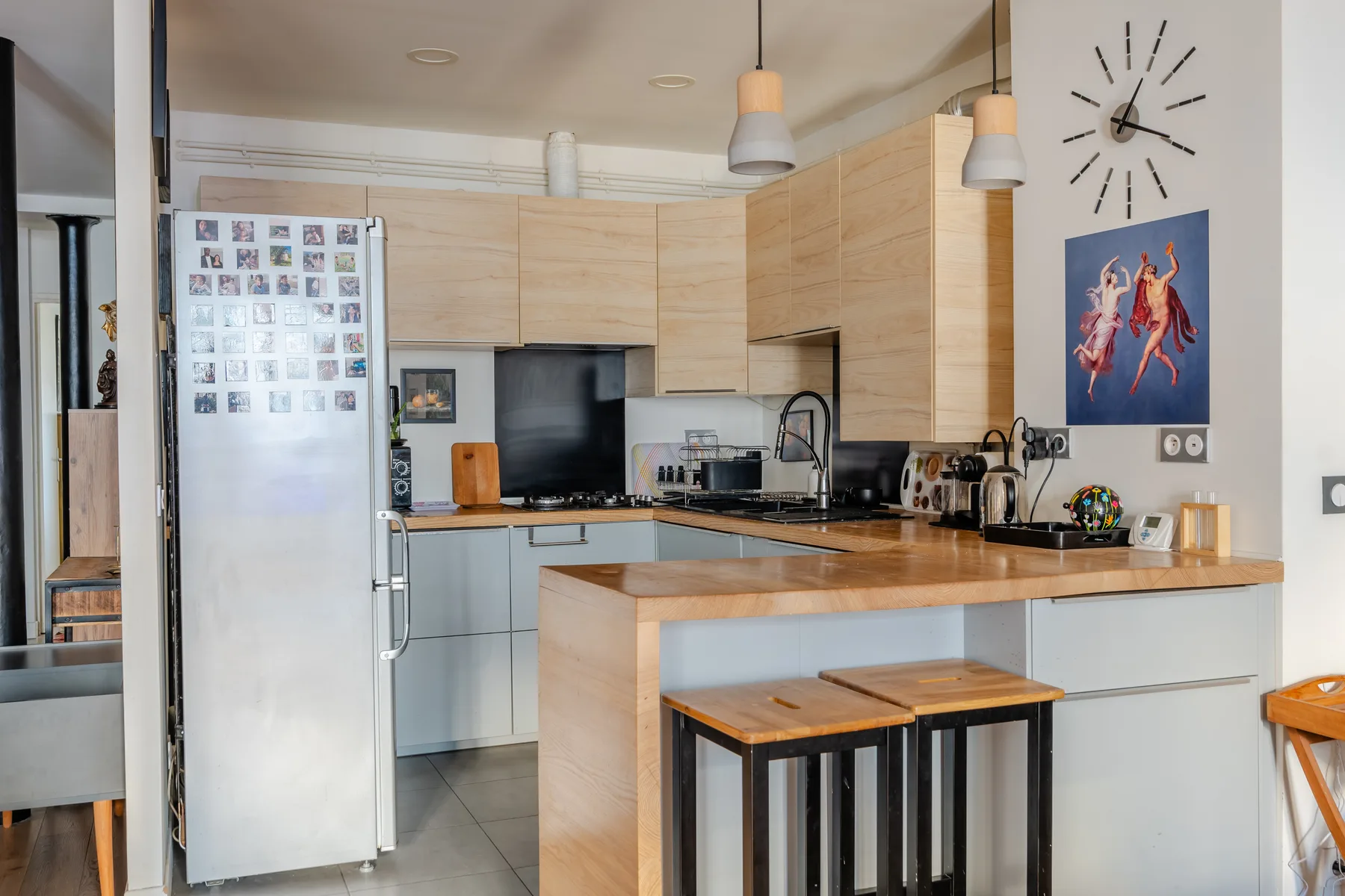 A bright kitchen with light wood cabinets and a counter with stools.