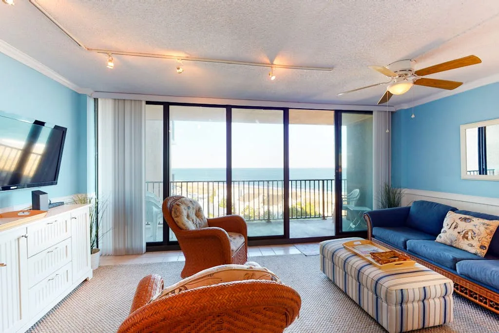 Living room with blue seating and glass doors opening onto a balcony.