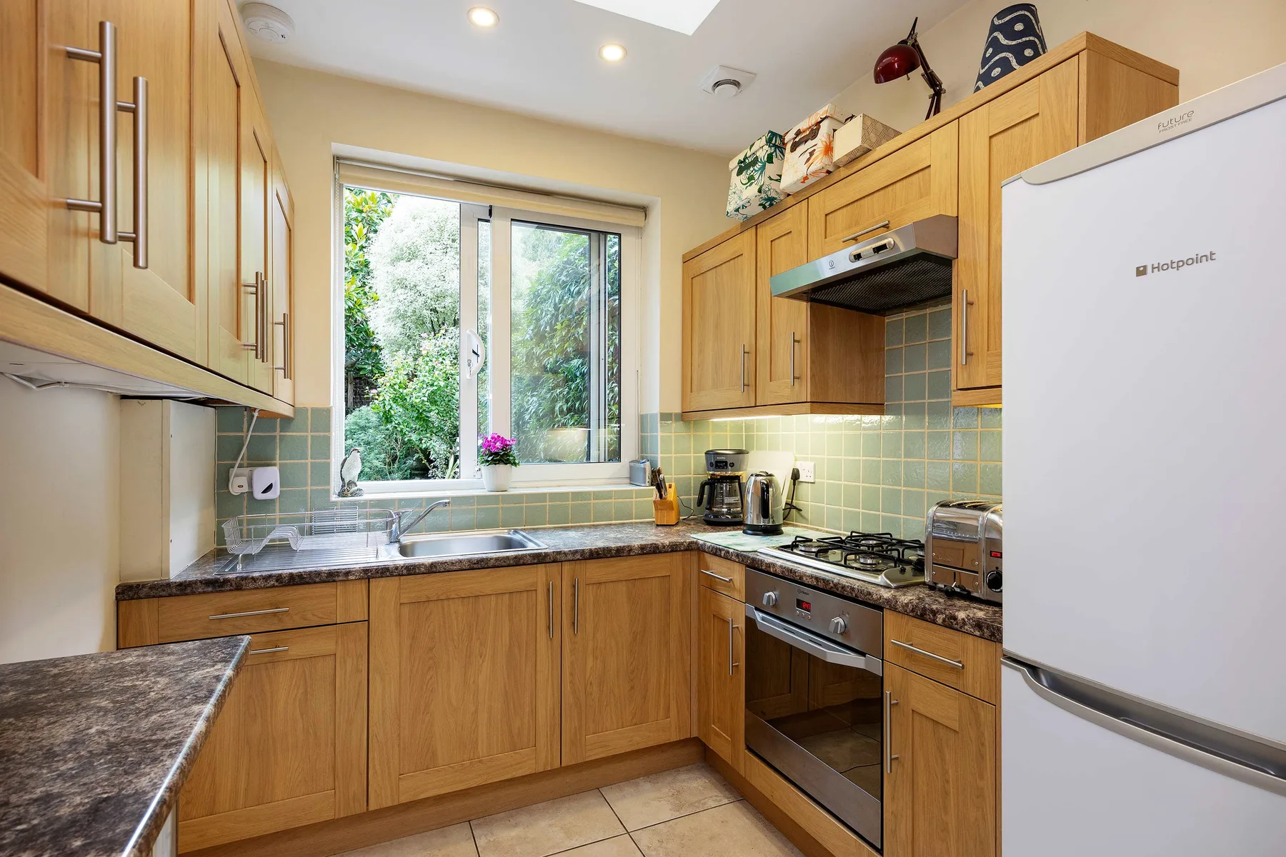 A bright kitchen with wooden cabinets, tiled backsplash, and a window.