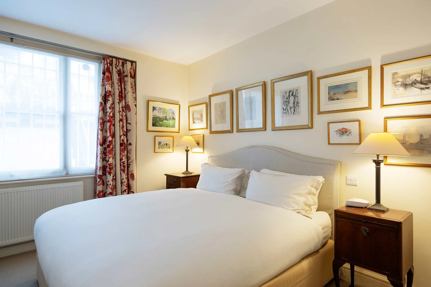 Bedroom with a large bed beneath a wall of framed artwork.