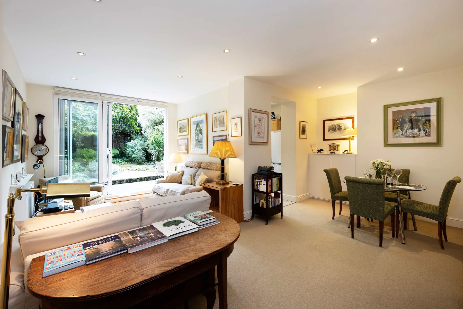 A bright living and dining room with seating, a dining table, and large windows.