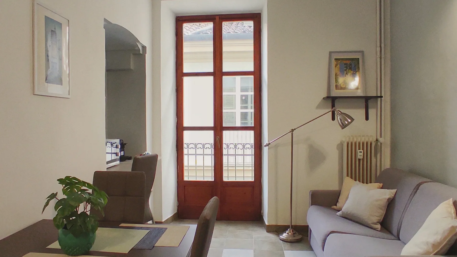 A living room with a sofa, floor lamp, and tall red-framed glass doors.