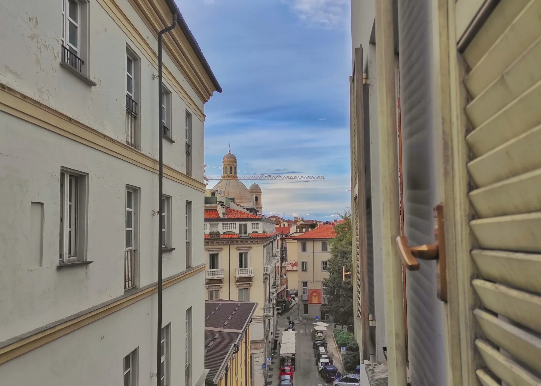 A narrow urban street is visible between buildings, with rooftops and blue sky beyond.