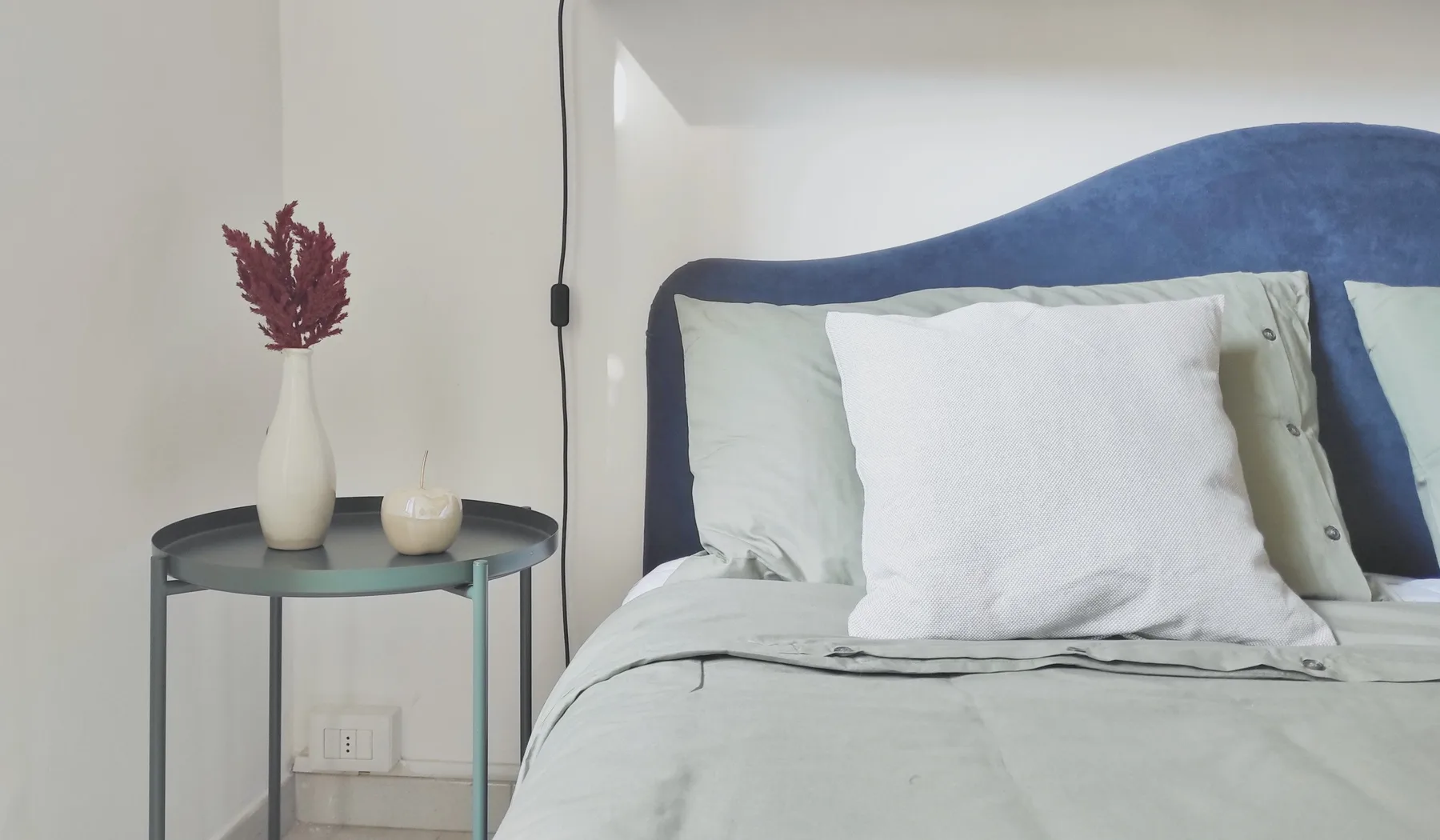 A bedroom with a bed and a small round bedside table.