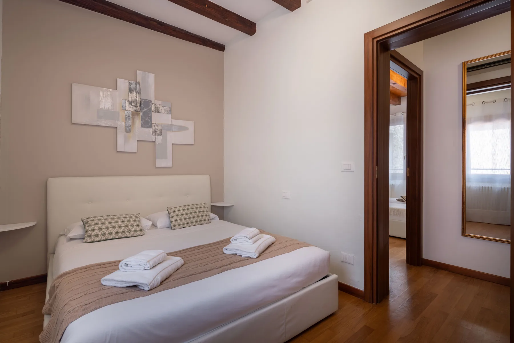 Un dormitorio con una cama bien hecha y arte abstracto en la pared.