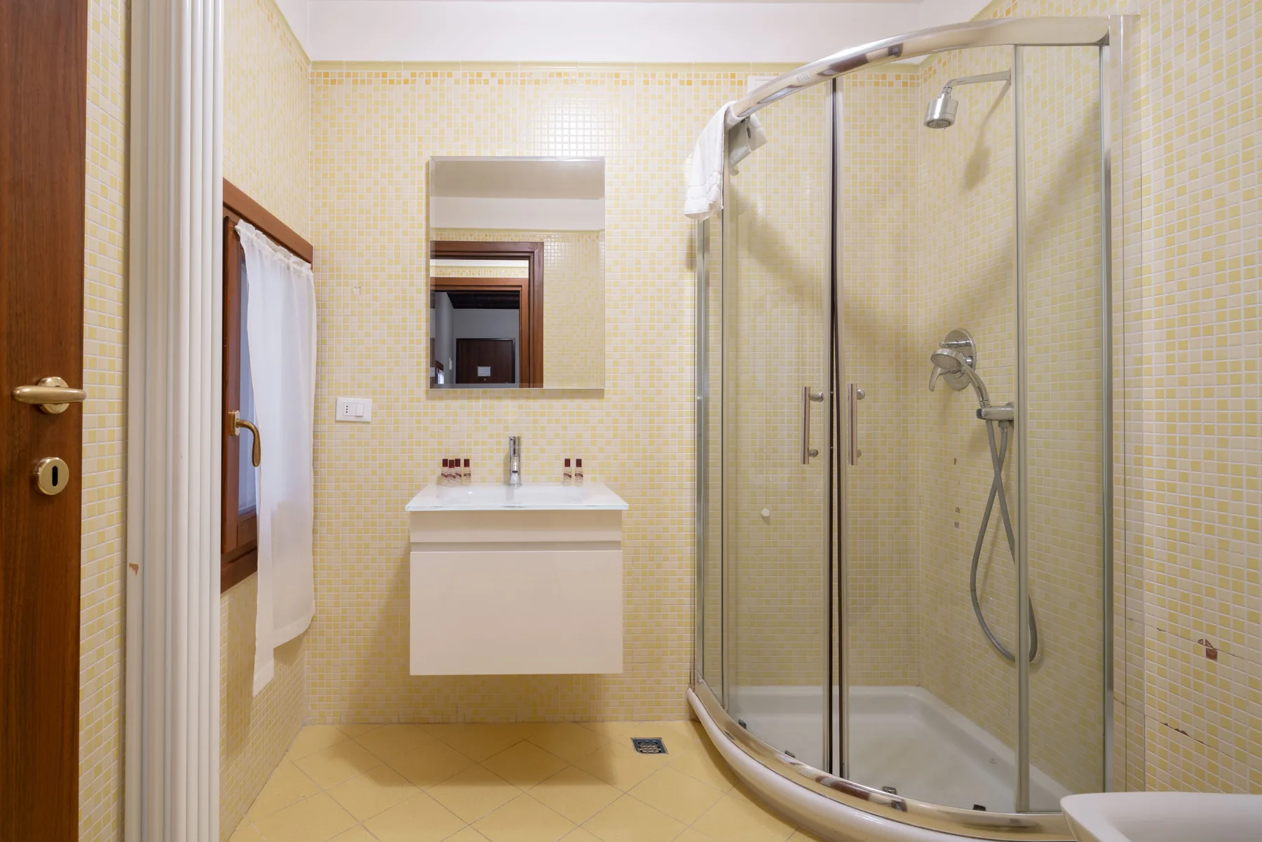 Un baño con azulejos, lavabo y ducha de cristal.