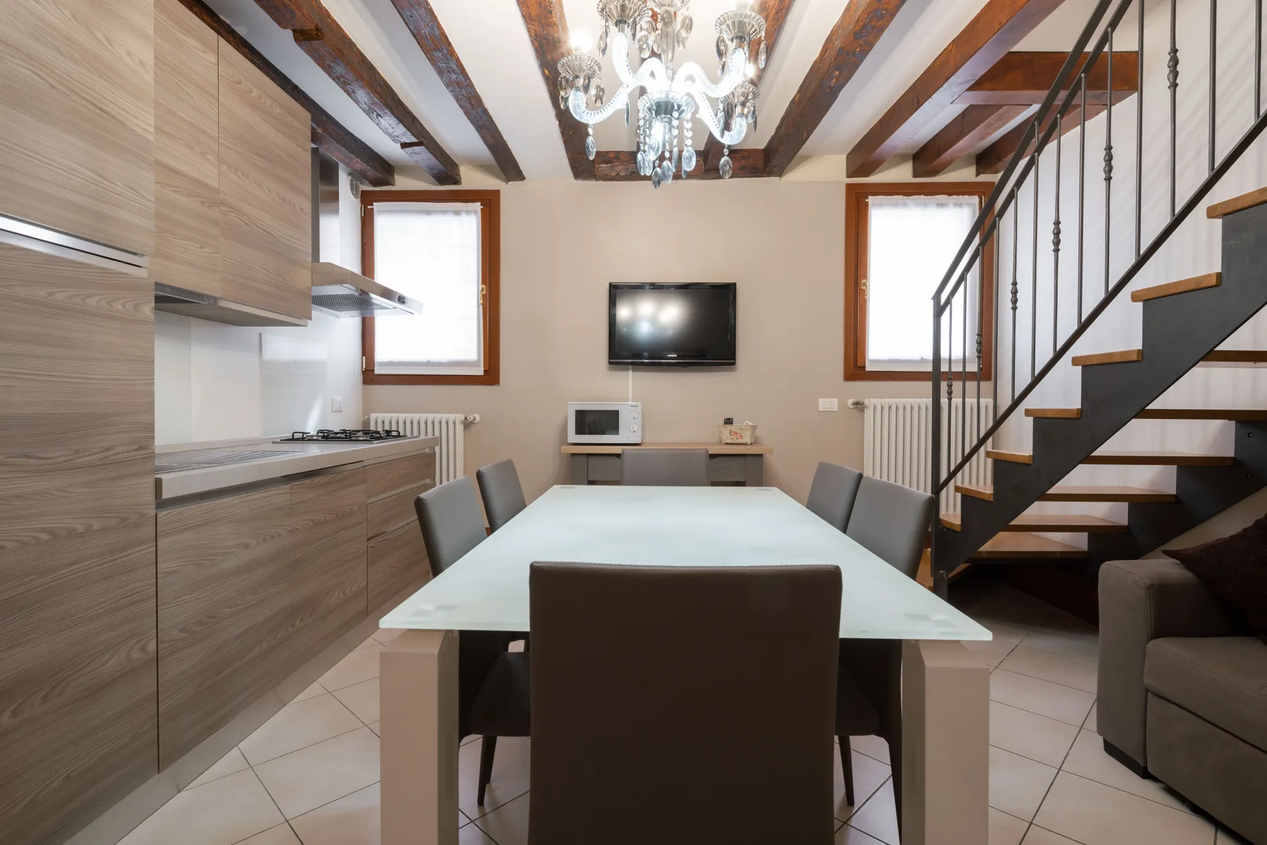 Un comedor con una mesa larga junto a una cocina y una escalera.