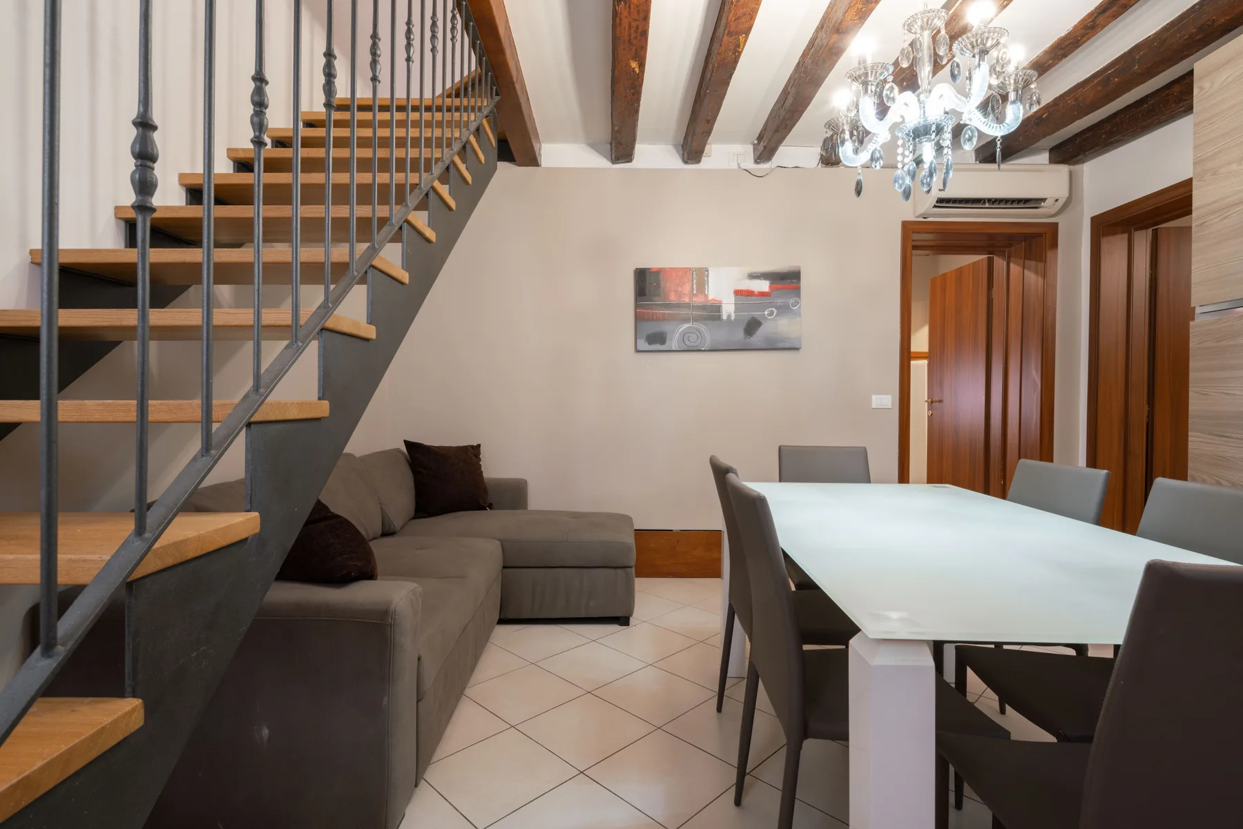 Un comedor y sala de estar con una mesa larga, asientos y una escalera.