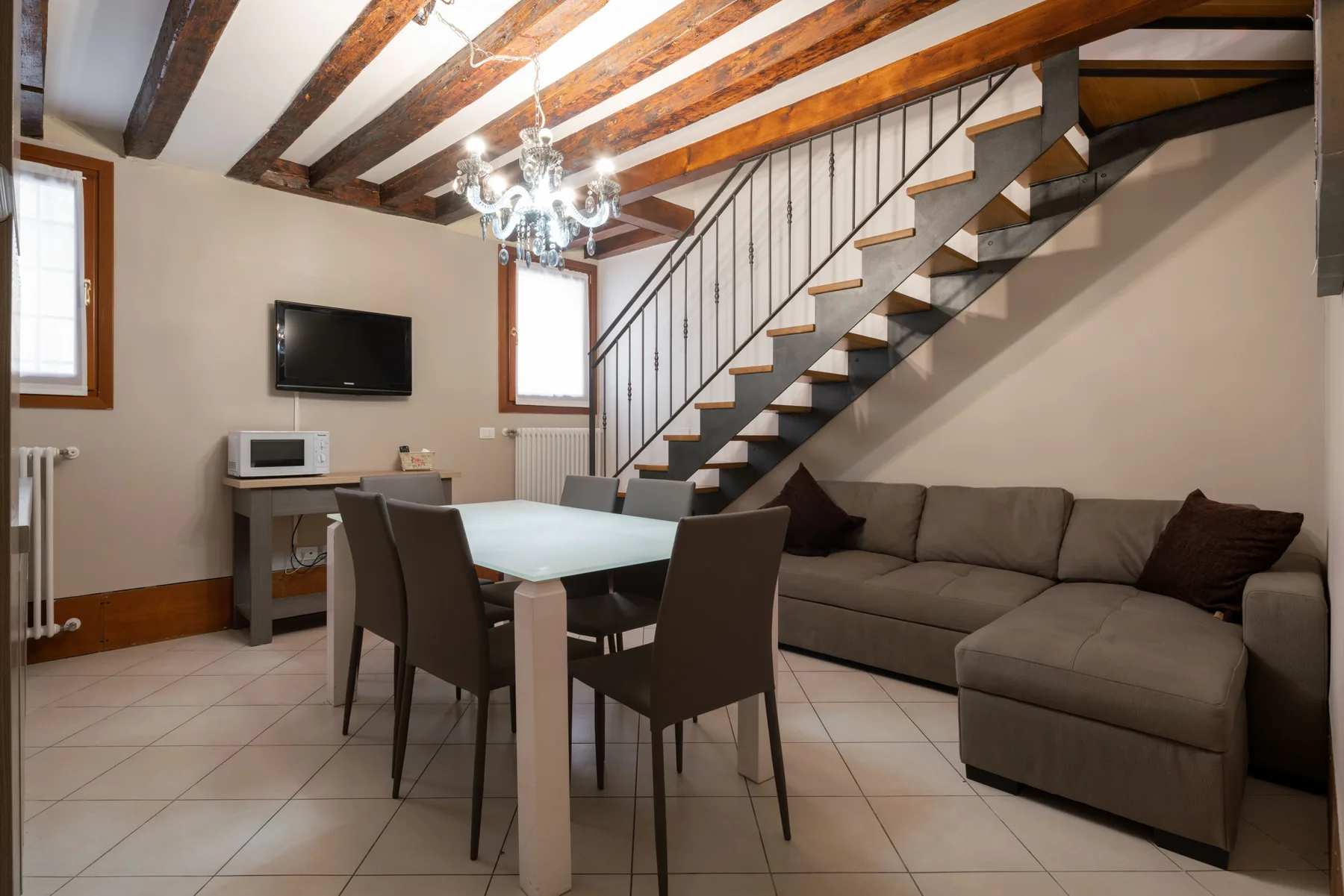 Una sala de estar y comedor con un sofá seccional y una escalera.