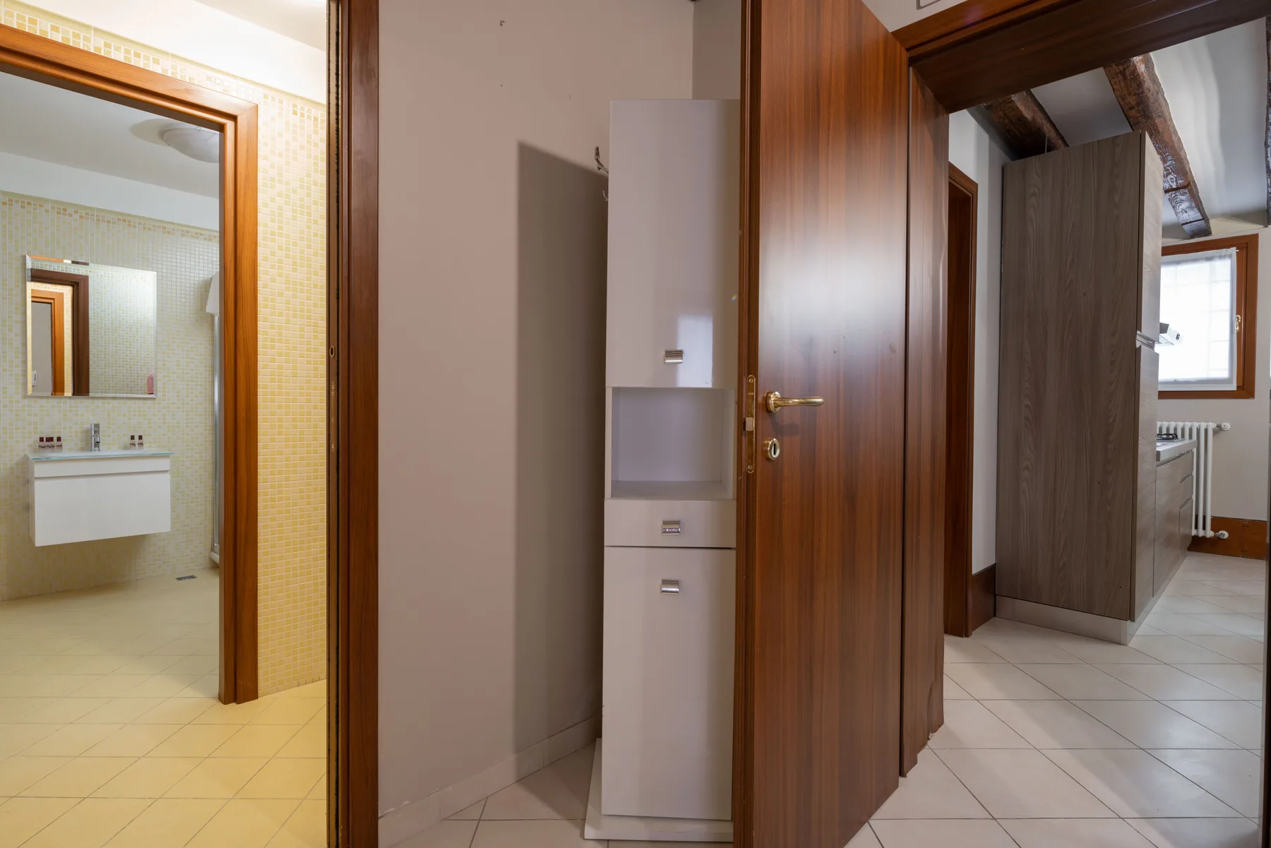Un pasillo interior con suelo de baldosas, puertas de madera y un armario empotrado.
