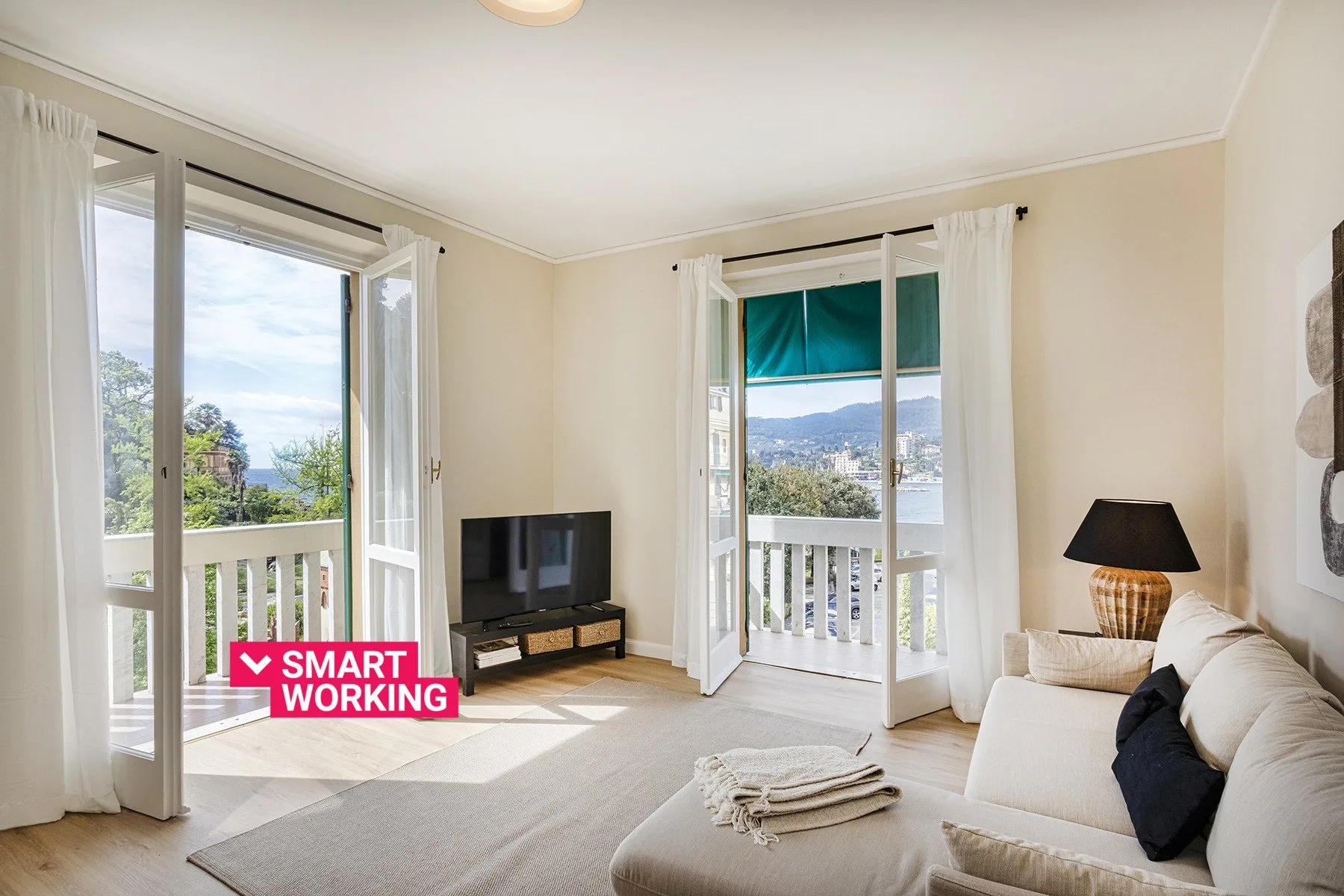 A bright living room with seating, a television, and doors opening onto a balcony.