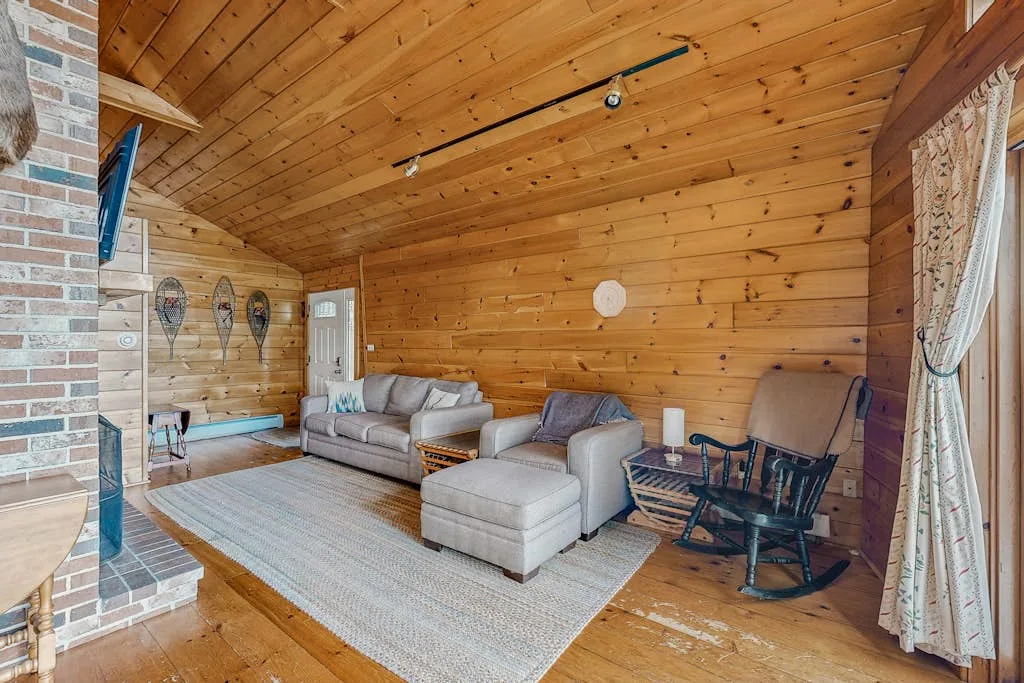 A wood-paneled living room with seating arranged around a rug.