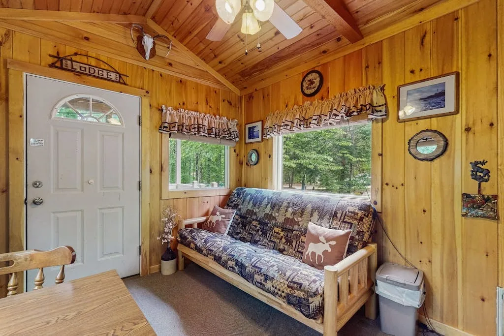 Una sala revestida de madera con un futón estampado debajo de las ventanas.
