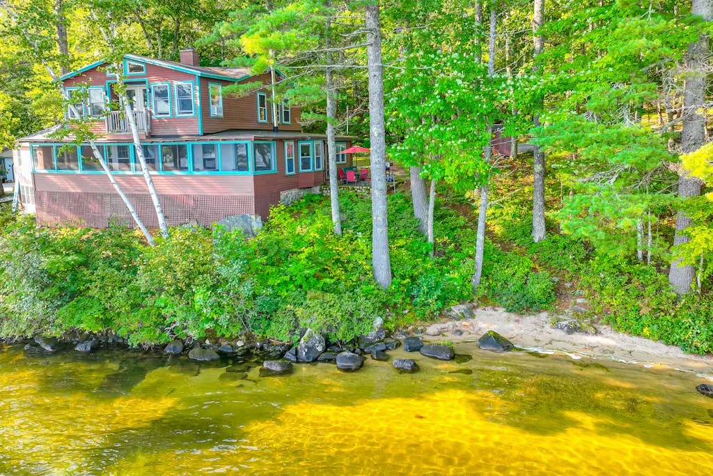Una casa junto al río, rodeada de árboles, se alza sobre un arroyo poco profundo.